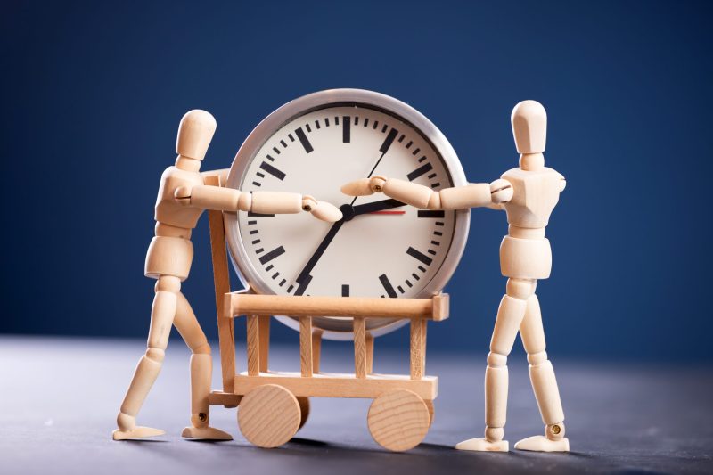 Two wooden figure holding a clock. Time is money, time management, hard working concept.